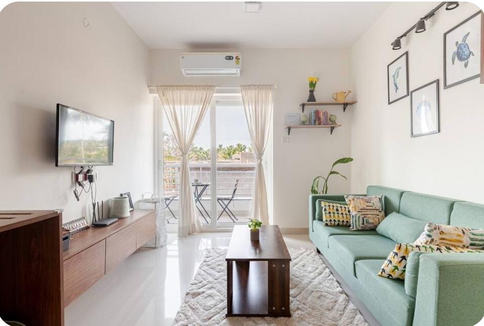 Bright living room with mint sofa and palm tree views
