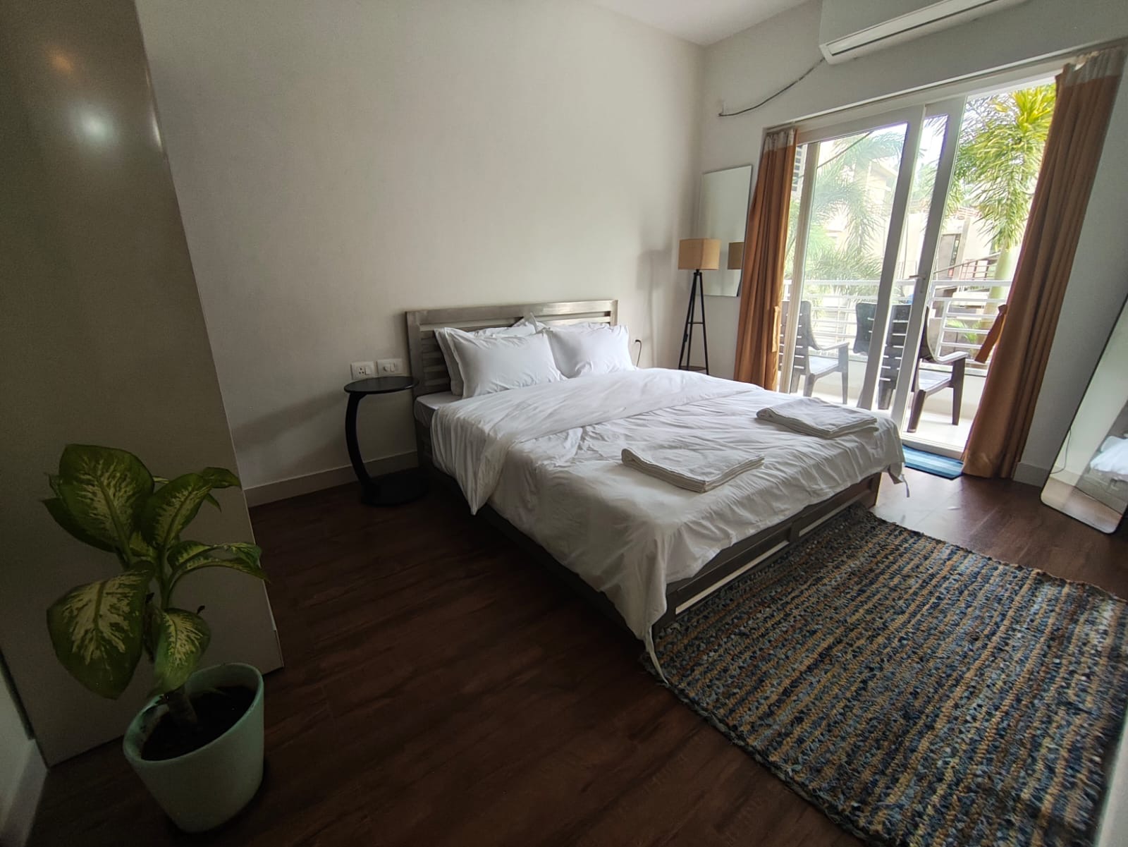 Bedroom with potted plant, woven rug, and balcony access