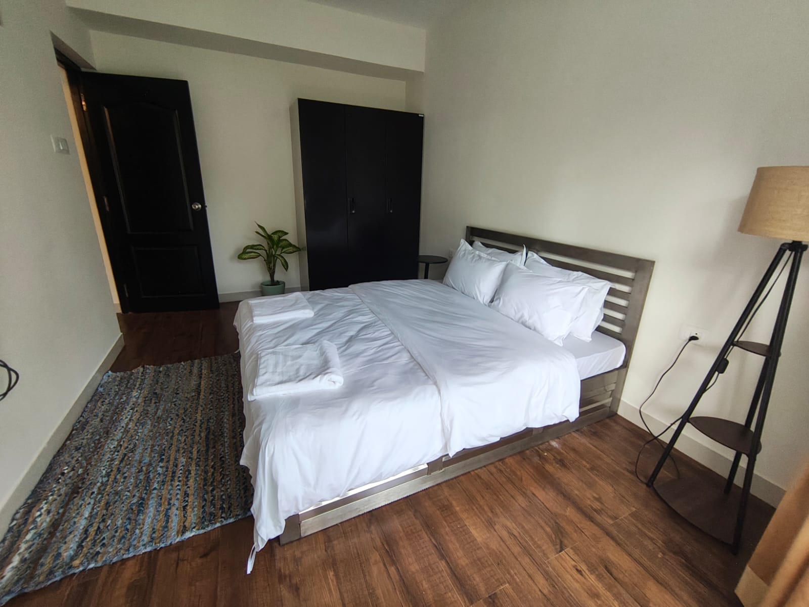 Bedroom with black wardrobe, full-length mirror, and queen bed